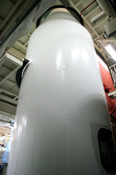 The white cylindrical skin of the rocket towers up to and through the ceiling. (46K JPEG)