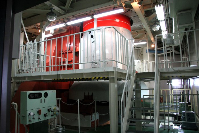 The white and flourescent orange body of the rocket dominates the center of the frame, surrounded by platforms and steps. (84K JPEG)