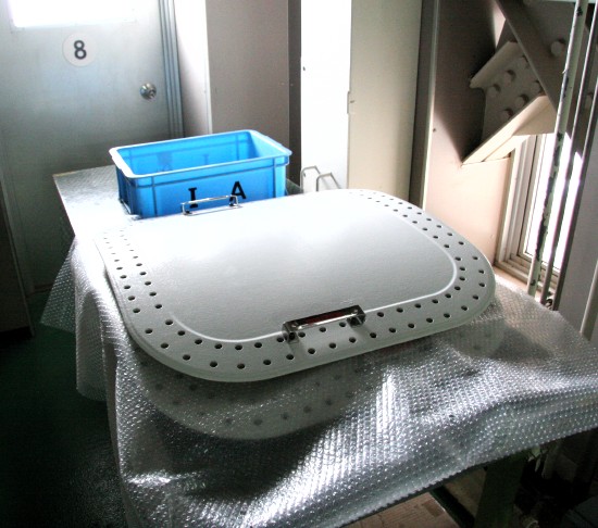 Two cylindrically curved square panels, about 50 centimeters on a side, rest on a table, with bubble wrap between them.  The 