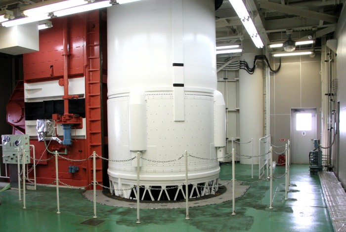 The pure white cylinder of the rocket's second stage protrudes through the floor, extending through the ceiling. (85K JPEG)