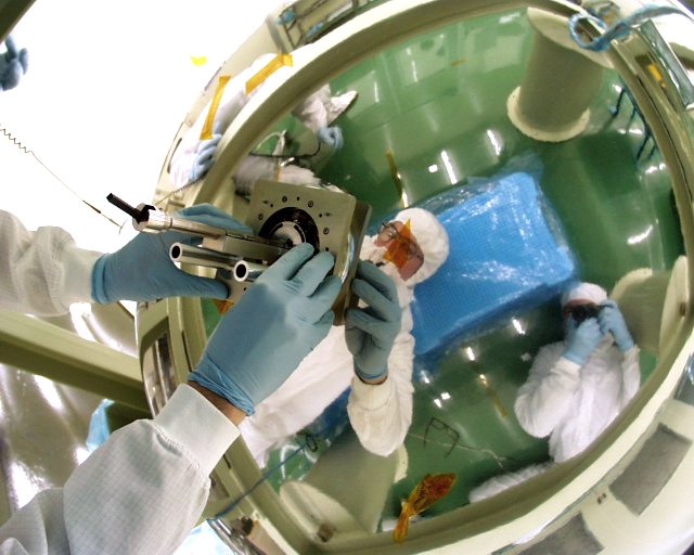 Gloved hands installing filter into a silvery dome. (59K JPEG)